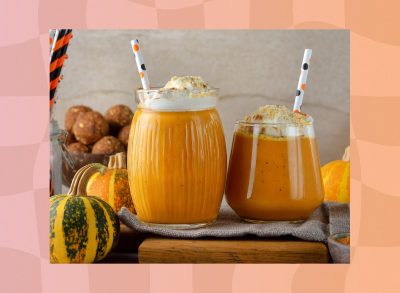 pumpkin smoothies in glasses with festive straws surrounded by pumpkins and gourds