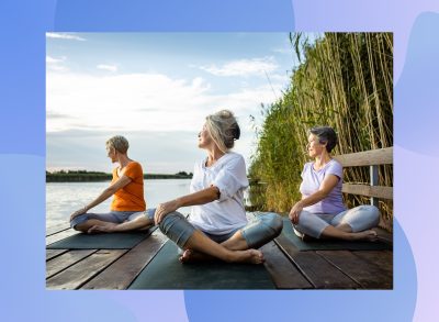 a group of senior women practicing yoga outdoors on a dock by a lake