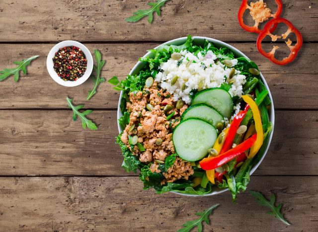 Healthy food concept. Paleo keto taco bowl with ground turkey, cauliflower rice, paprikas, cucumber, kale and pumpkin seeds. 