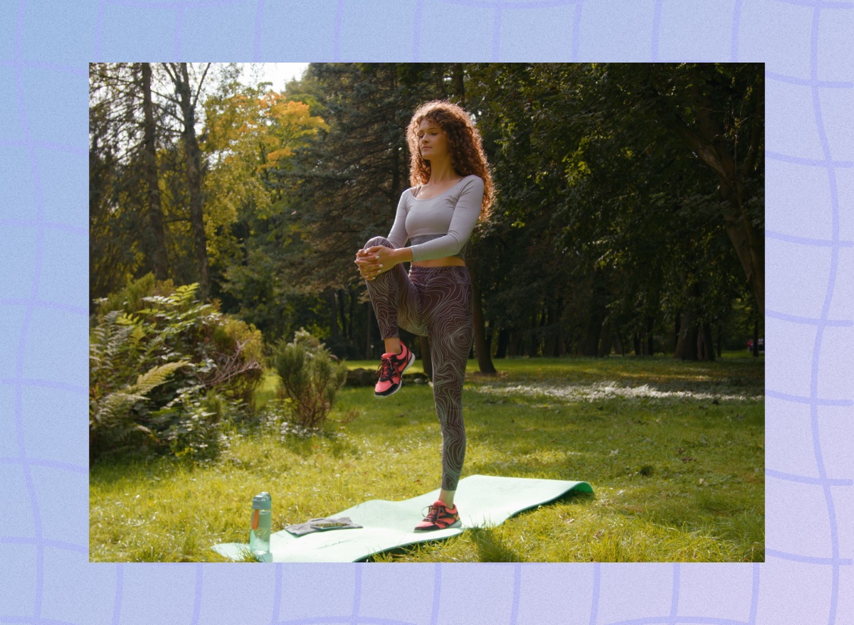 focused woman doing single-leg balance exercise on yoga mat in field on sunny day