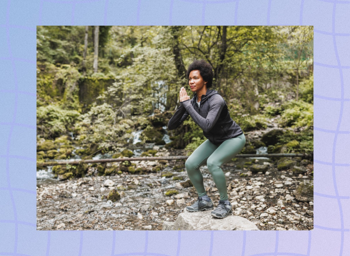 focused, mature woman doing squats while on nature hike