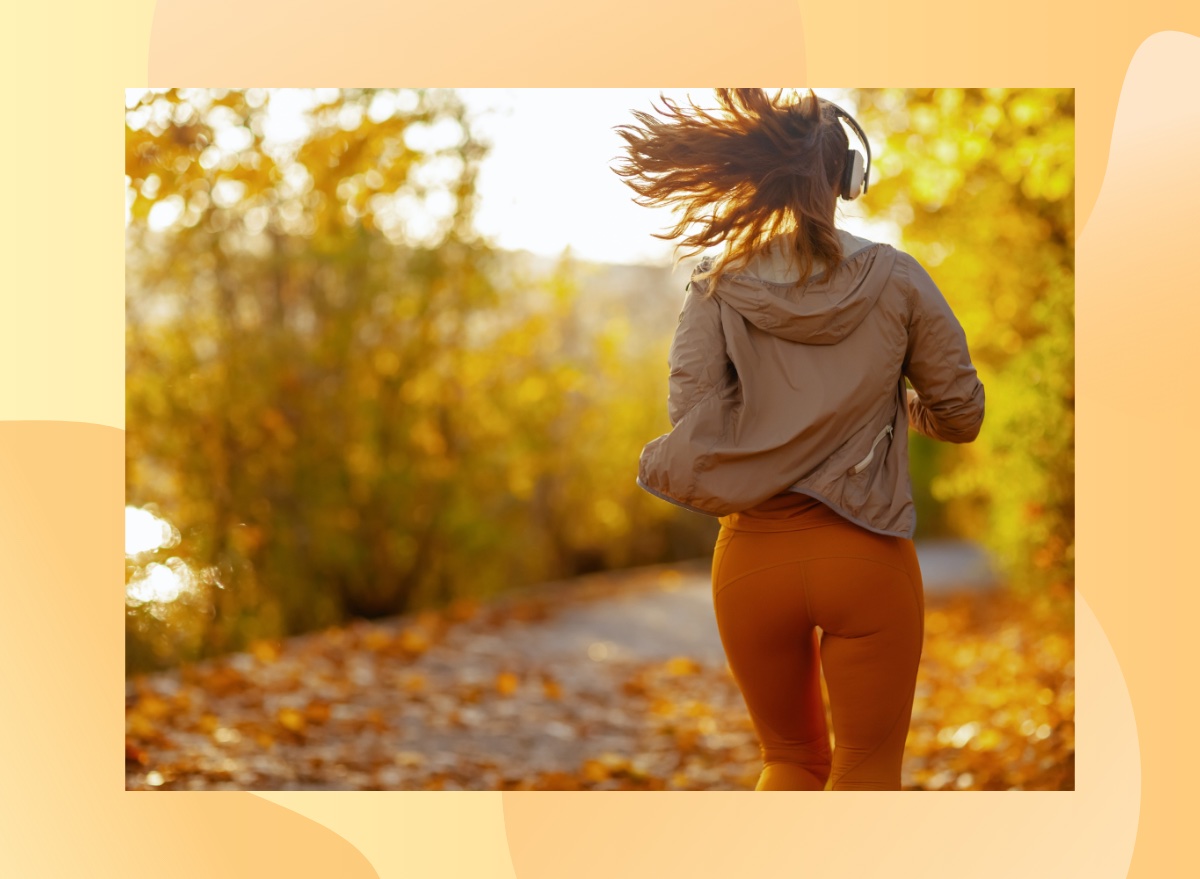 back view of a woman jogging outdoors on a sunny autumn day on a tree-lined trail