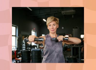 fit middle-aged woman lifting dumbbells in dark gym weight room