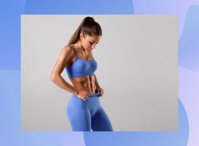 fit woman looking down at her six-pack abs