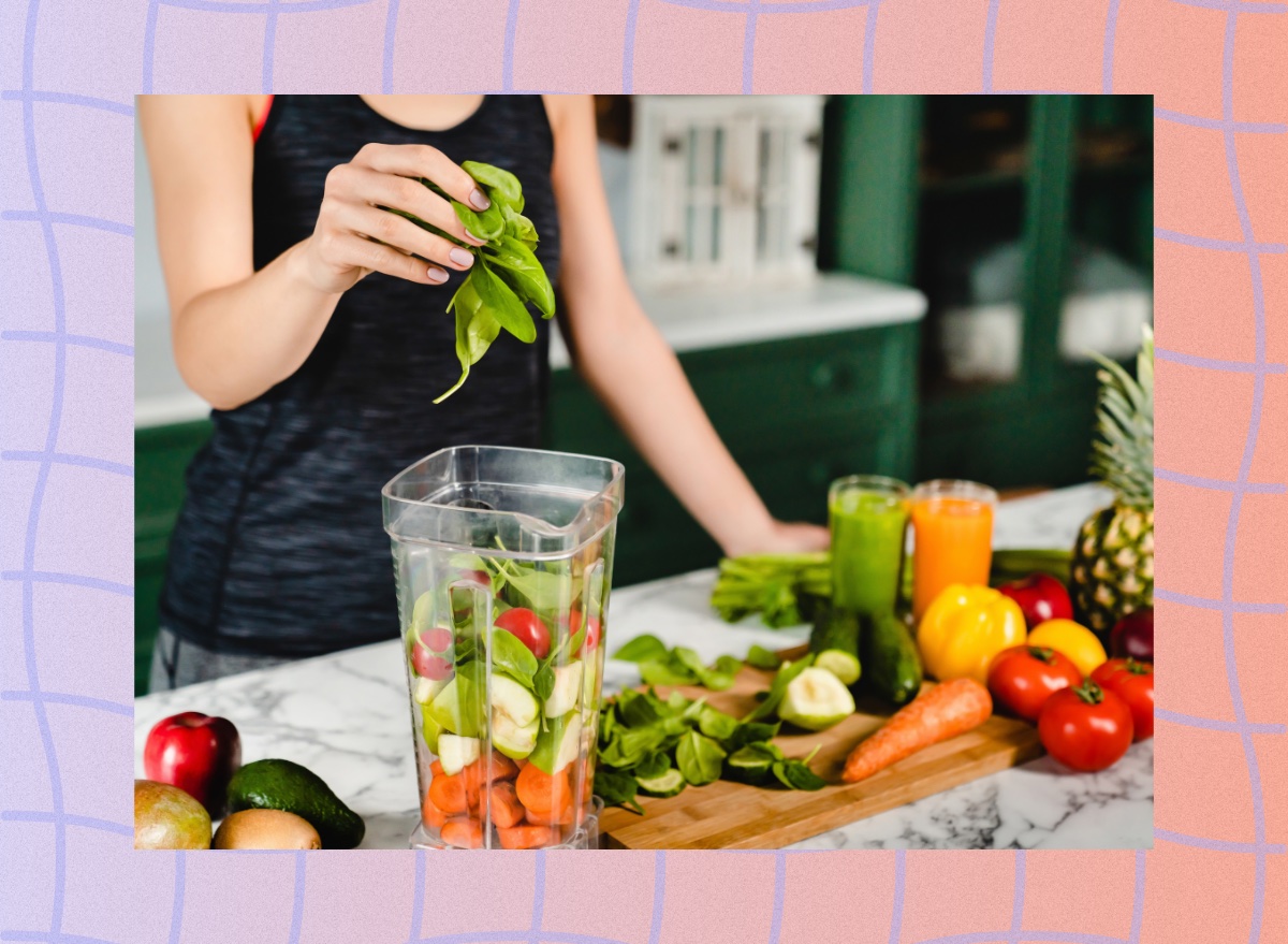 close-up of woman making fresh juice in blender with vegetables