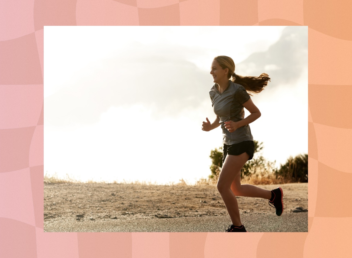 happy athletic woman running outdoors through mountain roads on overcast day