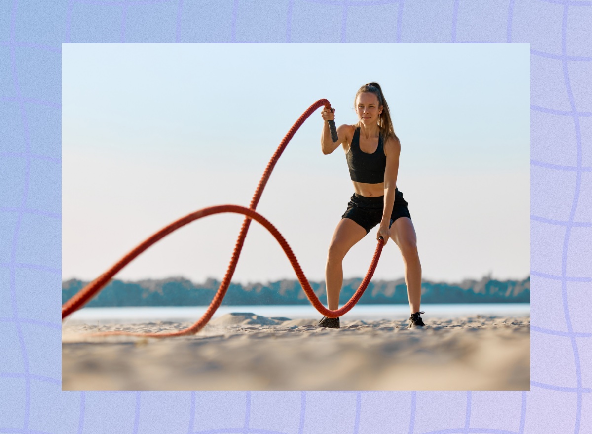 fit woman working out with battle ropes on the beach