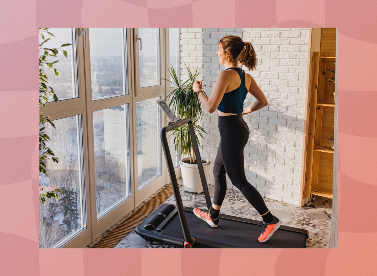 woman walking on treadmill in apartment in front of floor-to-ceiling windows