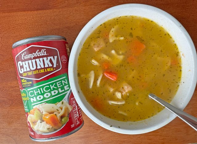 A can of Campbell's Chunky Chicken Noodle beside a bowl of the soup