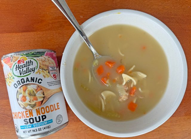 A can of Health Valley Organic Chicken Noodle Soup beside a bowl of the soup