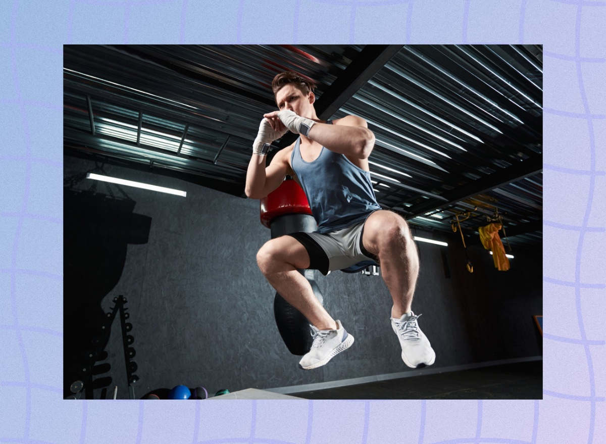 muscular man mid-air doing box jumps in a dark gym setup