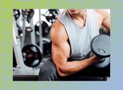 close-up of muscular man doing a seated bicep curl at the gym