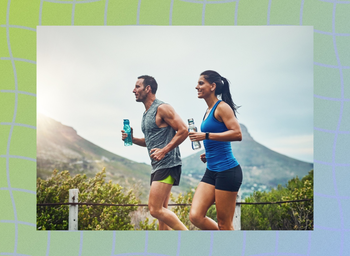 fit, happy couple running through the mountains on a road on a sunny, semi-cloudy day