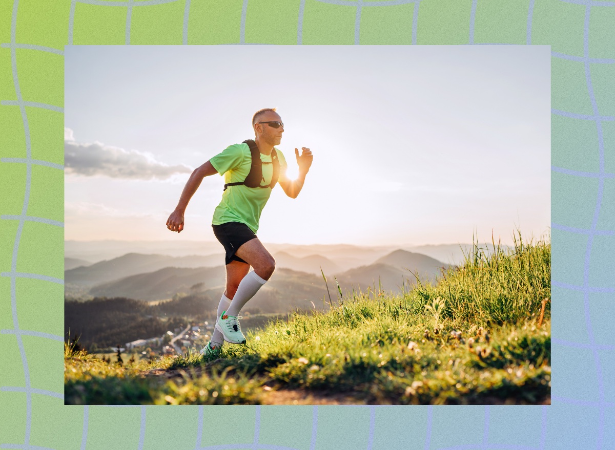 fit, determined middle-aged man in bright green t-shirt and shorts running uphill with rucking backpack or weighted vest at sunset