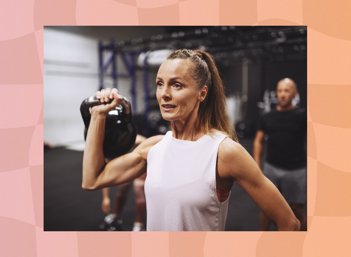 fit, mature brunette woman lifting a kettlebell in the gym during a workout class