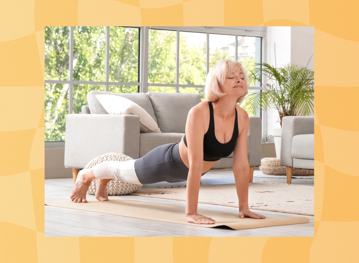 middle-aged blonde woman doing yoga plank exercise on mat in her bright living room