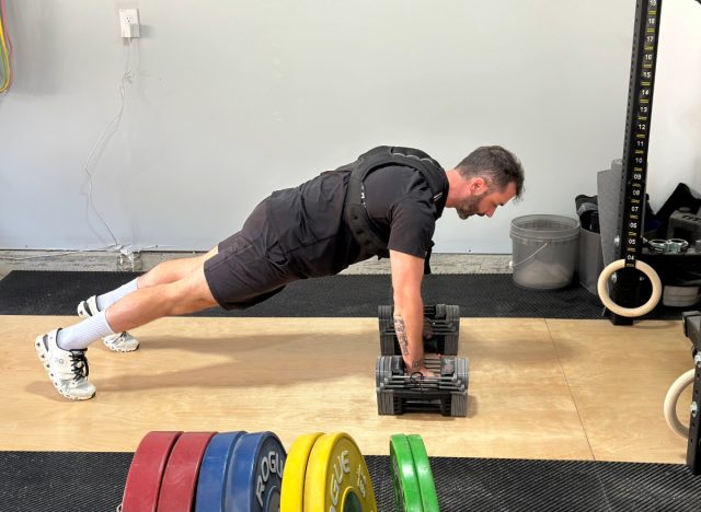 trainer wearing a weighted vest while doing a high plank