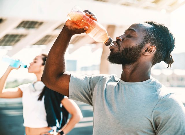 Fitness african athlete drinking energy drink outdoor - Fit people resting taking a break after workout - Healthy lifestyle concept