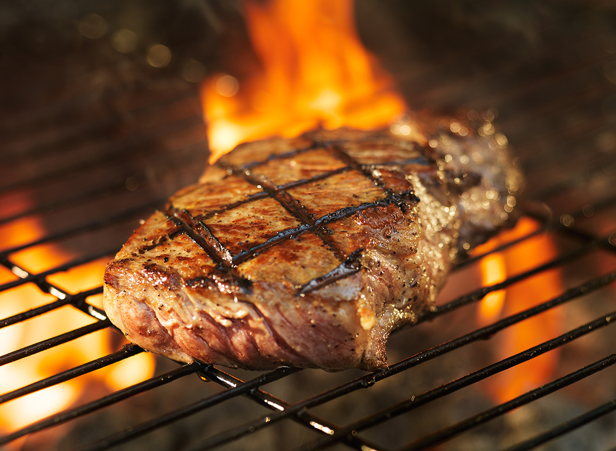 beef steak cooking over flaming grill