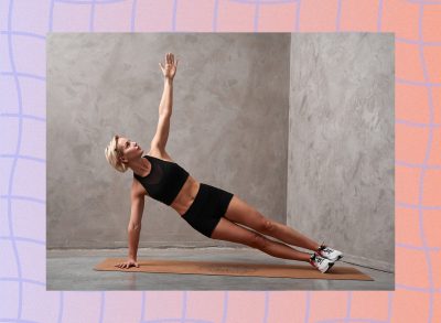 fit blonde woman doing a side plank exercise in front of grey backdrop