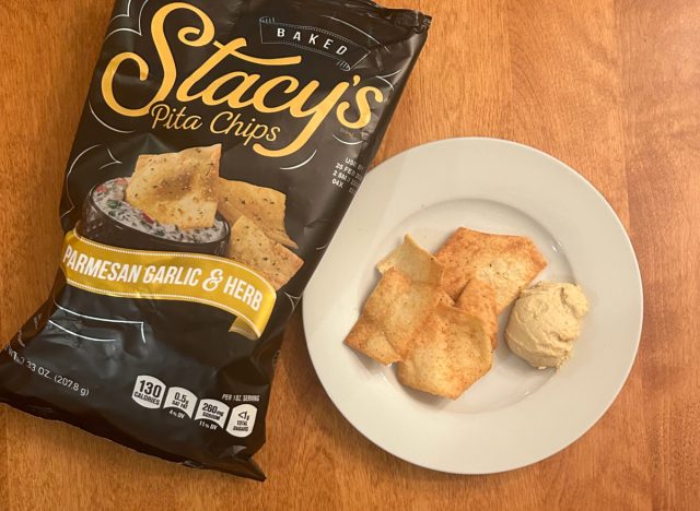 Stacy's Parmesan Garlic & Herb pita chips on a plate with hummus next to a bag of the pita chips