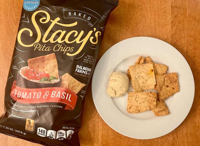 Stacy's Tomato & Basil pita chips on a plate with hummus next to a bag of the pita chips