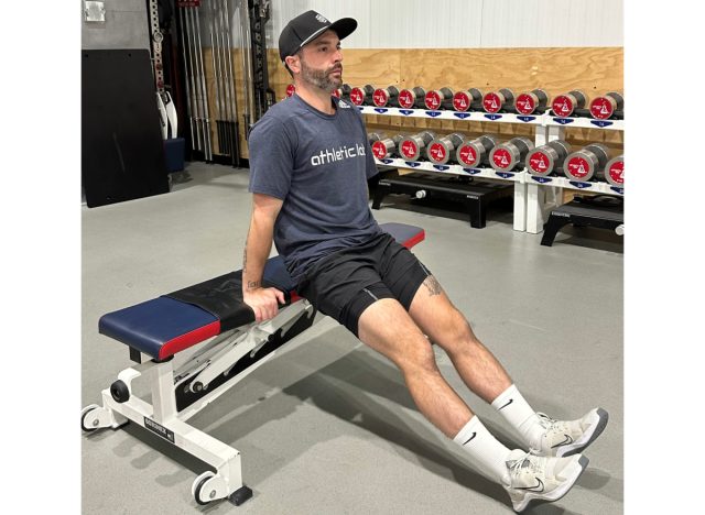 trainer doing a tricep dip from a bench