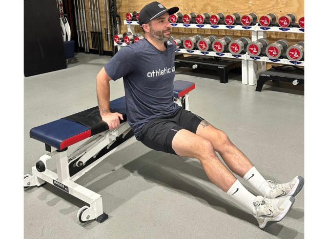 trainer lowering into a tricep dip from bench