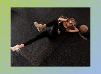 fit woman doing bicycle crunches on black yoga mat in dark gym setting