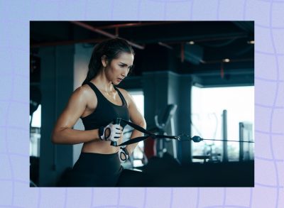 focused brunette woman doing a single-arm cable row exercise in dark gym