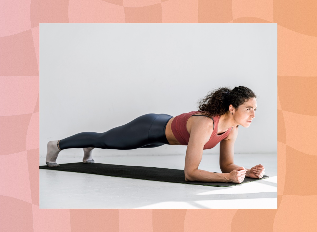 focused brunette woman doing a forearm plank on a yoga mat