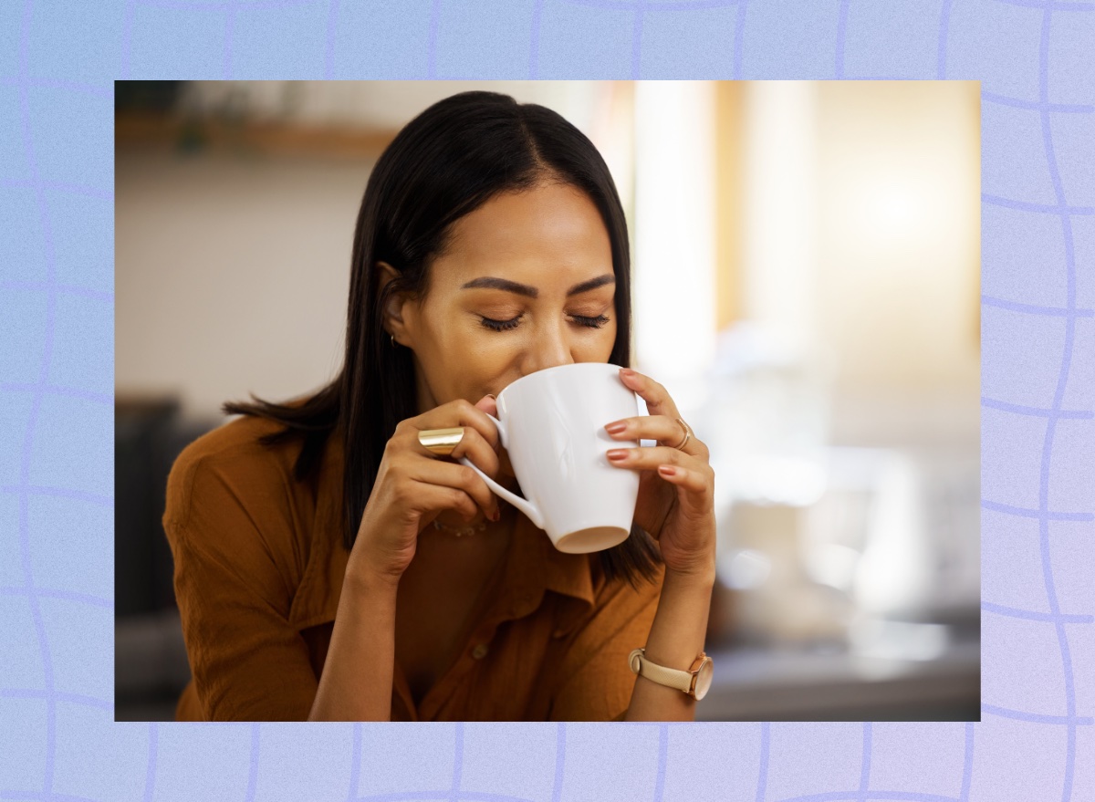 brunette woman drinking a hot beverage out of mug in bright kitchen