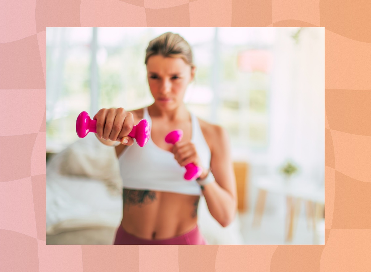 fit blonde woman working out with dumbbells at home in bright space with the camera focus on the dumbbells