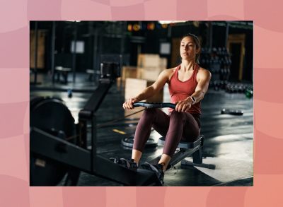 fit, focused brunette woman using a rowing machine at the gym