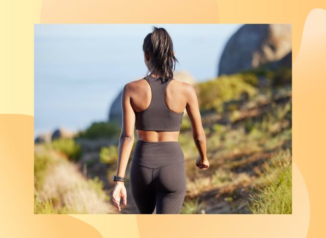 Vue arrière de la femme brune en forme marchant sur un chemin près de l'océan pour faire de l'exercice