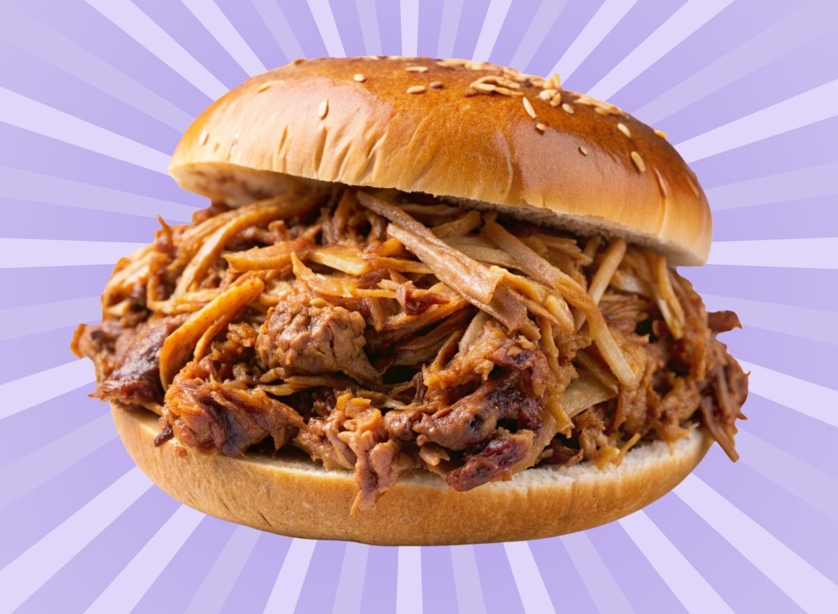 A closeup of a pulled pork sandwich set against a vibrant background.