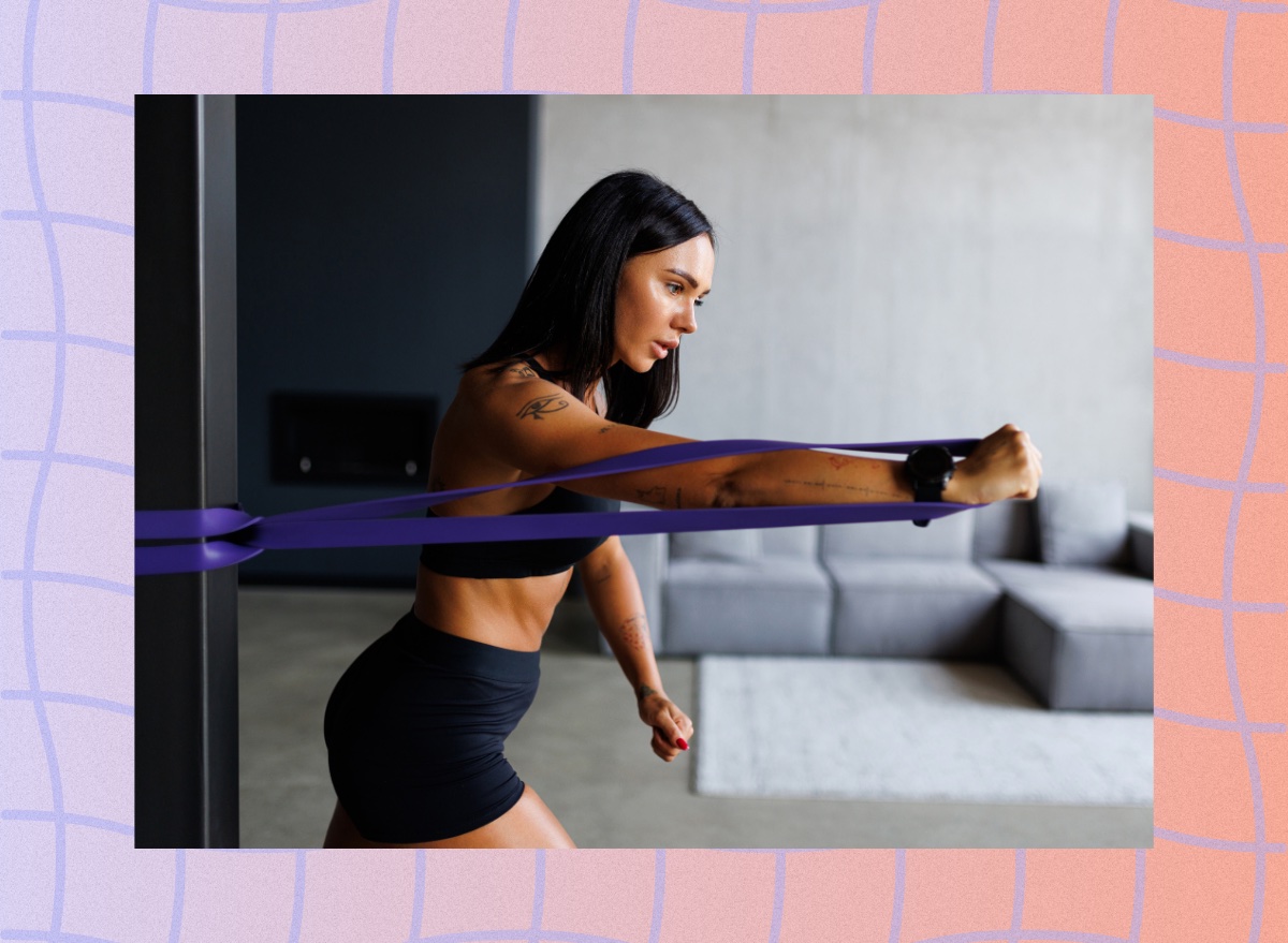 fit, focused woman doing a resistance band rotation exercise at home