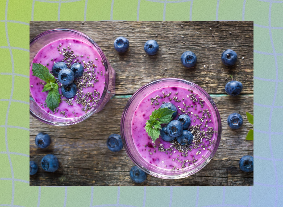 blueberry chia smoothie in two cups on wooden table, surrounded by fresh blueberries