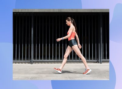 fit, focused brunette woman walking outdoors on sidewalk for exercise