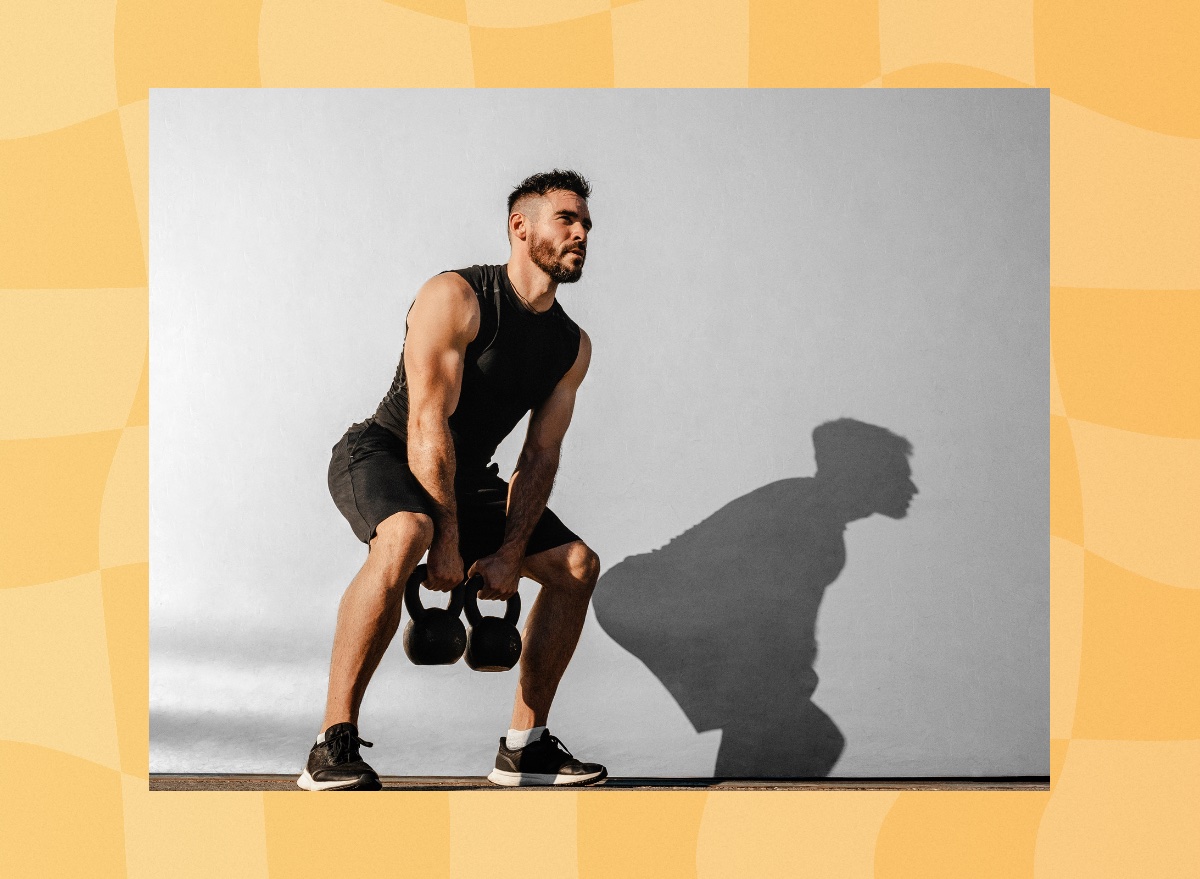 focused, muscular man doing kettlebell squat