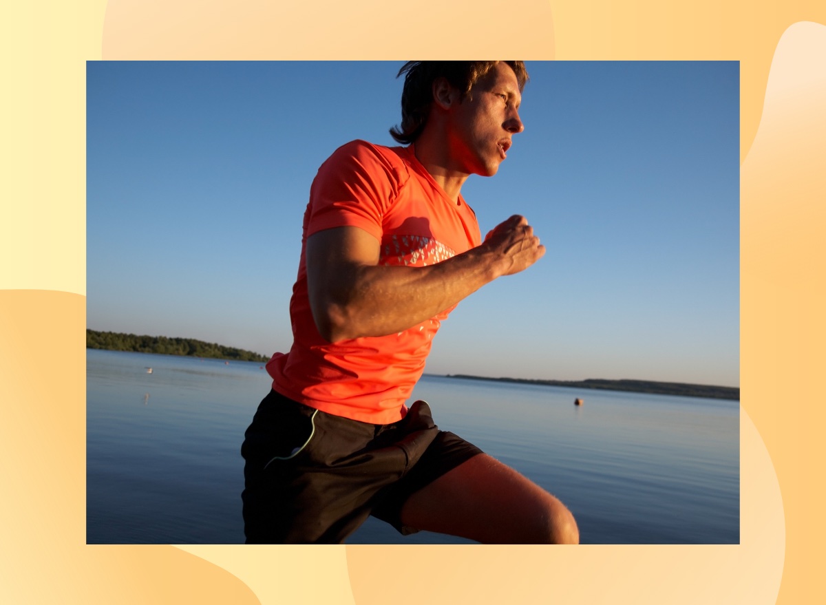 fit, focused man running alongside lake beach at sunset