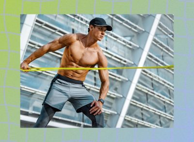 muscular, shirtless man using resistance band during workout outdoors