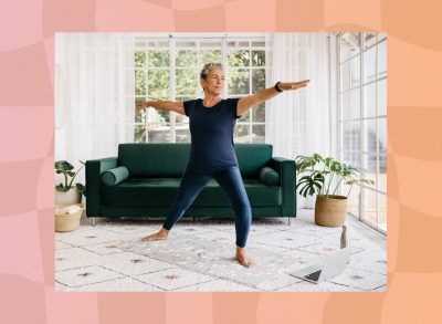 mature woman doing a balance yoga exercise in bright living room