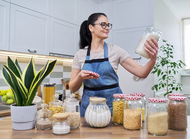 Smiling woman in the kitchen with jars of stored food.