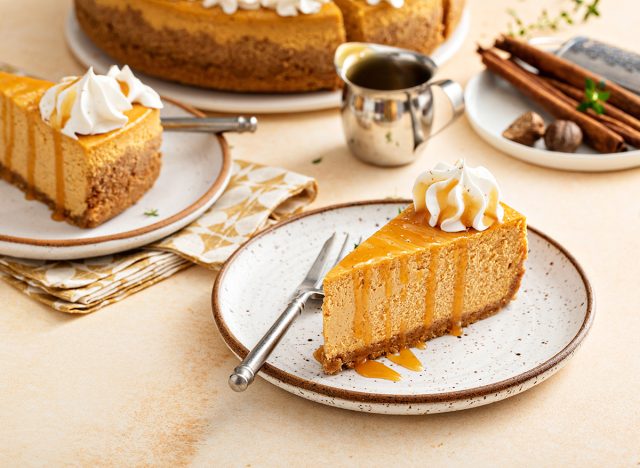 Pumpkin cheesecake with fall spices topped with whipped cream, dessert for Thanksgiving, a slice cut with caramel sauce