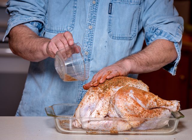 Adding a dry brine spice rub to a raw turkey