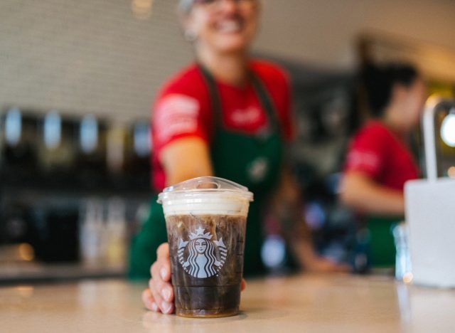 starbucks barista handing a cup of iced coffee to a customer