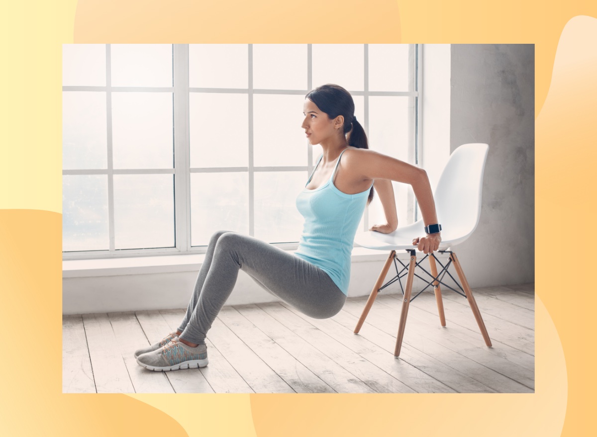 focused woman doing chair tricep dip exercise in bright living space