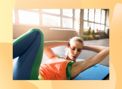 woman doing mat exercise for her abs in bright gym surrounded by windows