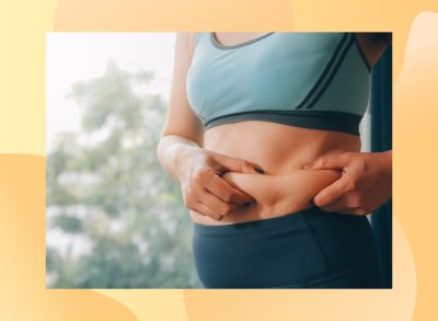 close-up of woman in athletic outfit holding excess belly fat